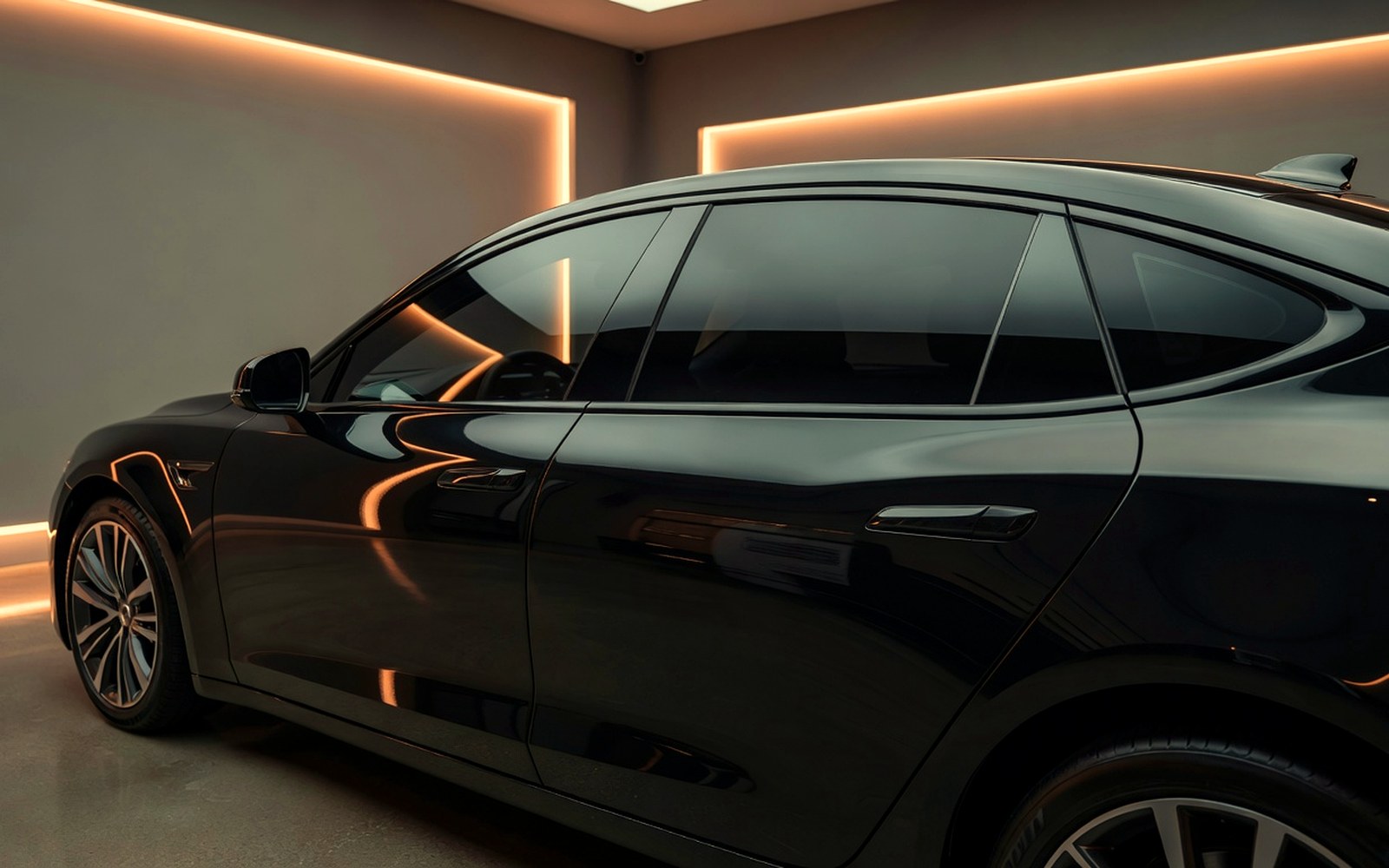 Clean sedan side profile with fresh automotive window tint in a premium shop bay